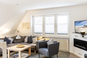 A modern living room with a sofa, armchair, and coffee table. - Apartment 4 (ID 152), Germany (Sankt Peter-Ording)