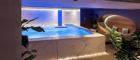 A spa area with a hot tub, marble walls, and a wooden seating area.