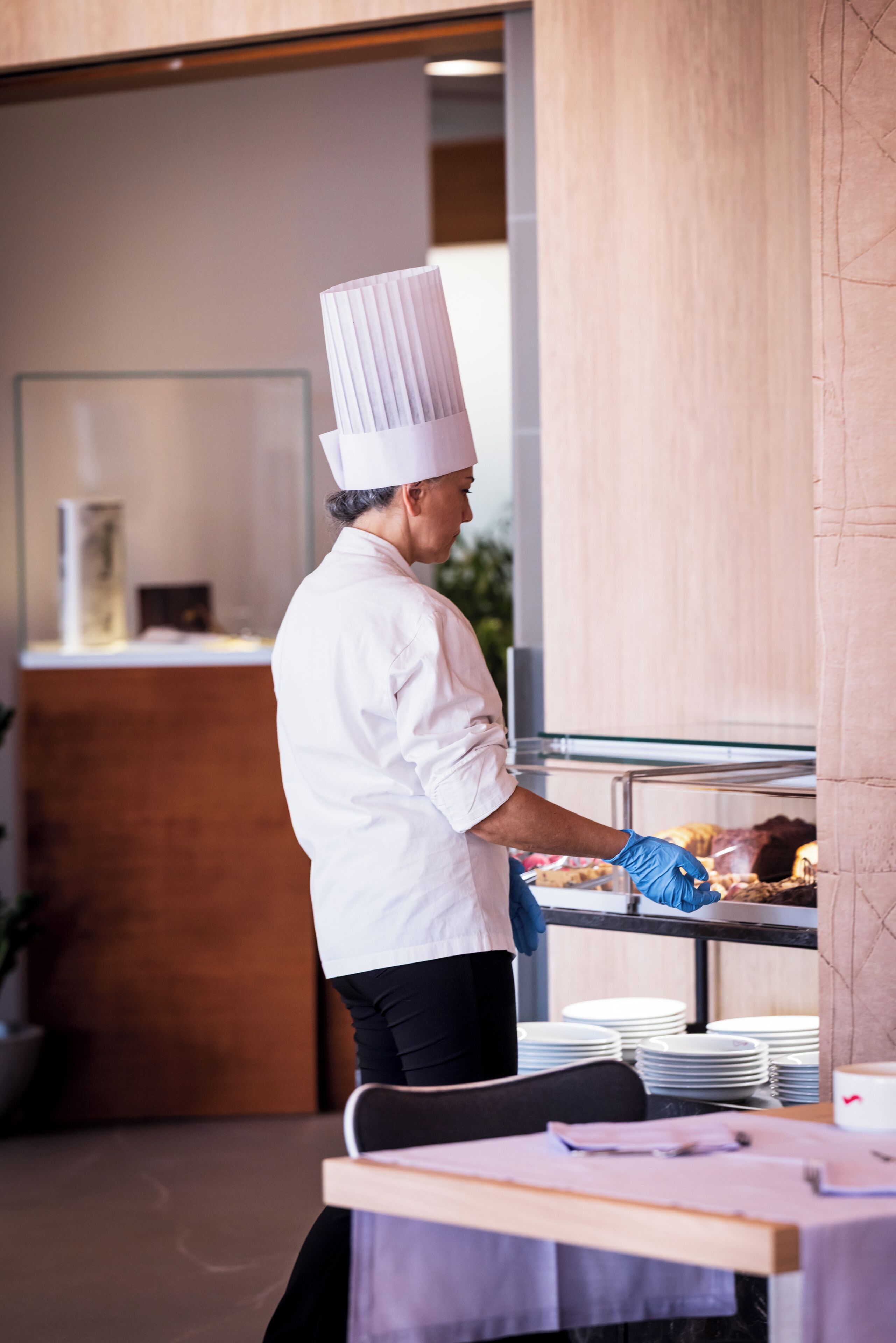 Un chef con uniforme y gorro blanco preparando comida en un bufé.