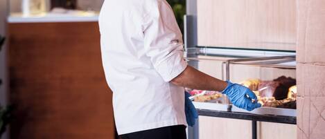Un chef con uniforme y gorro blanco preparando comida en un bufé.