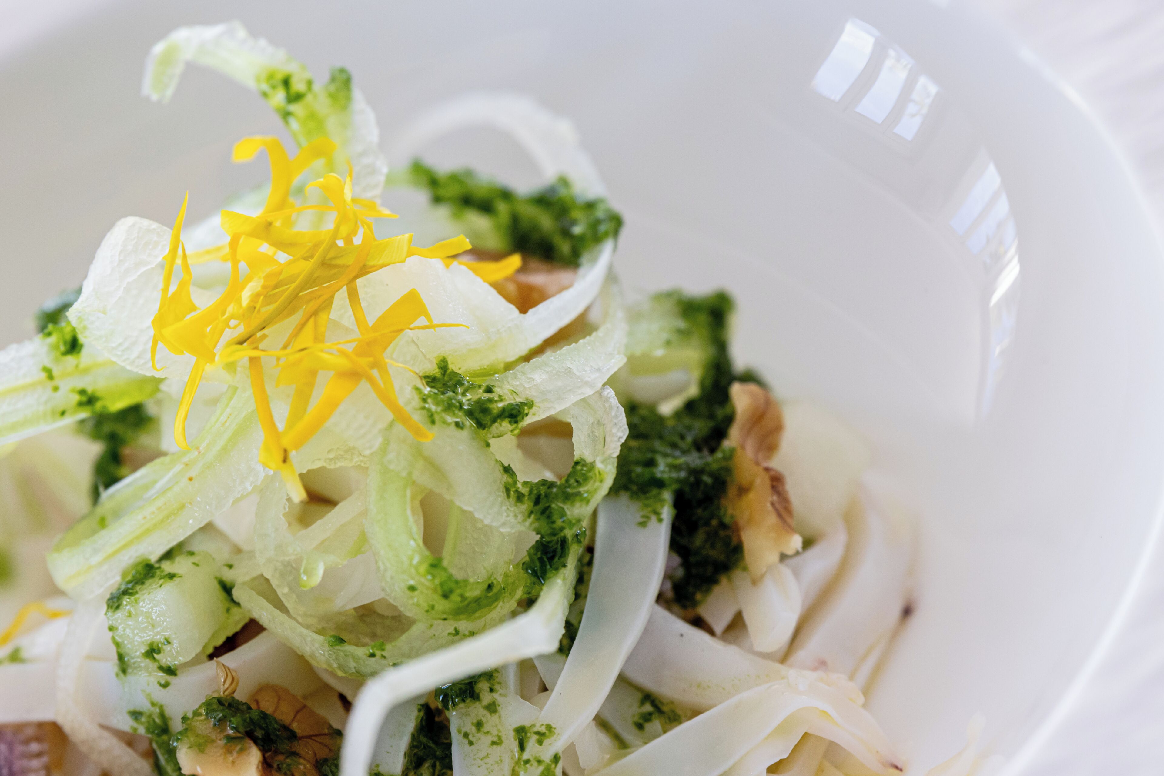 A bowl of food with shredded vegetables and herbs.
