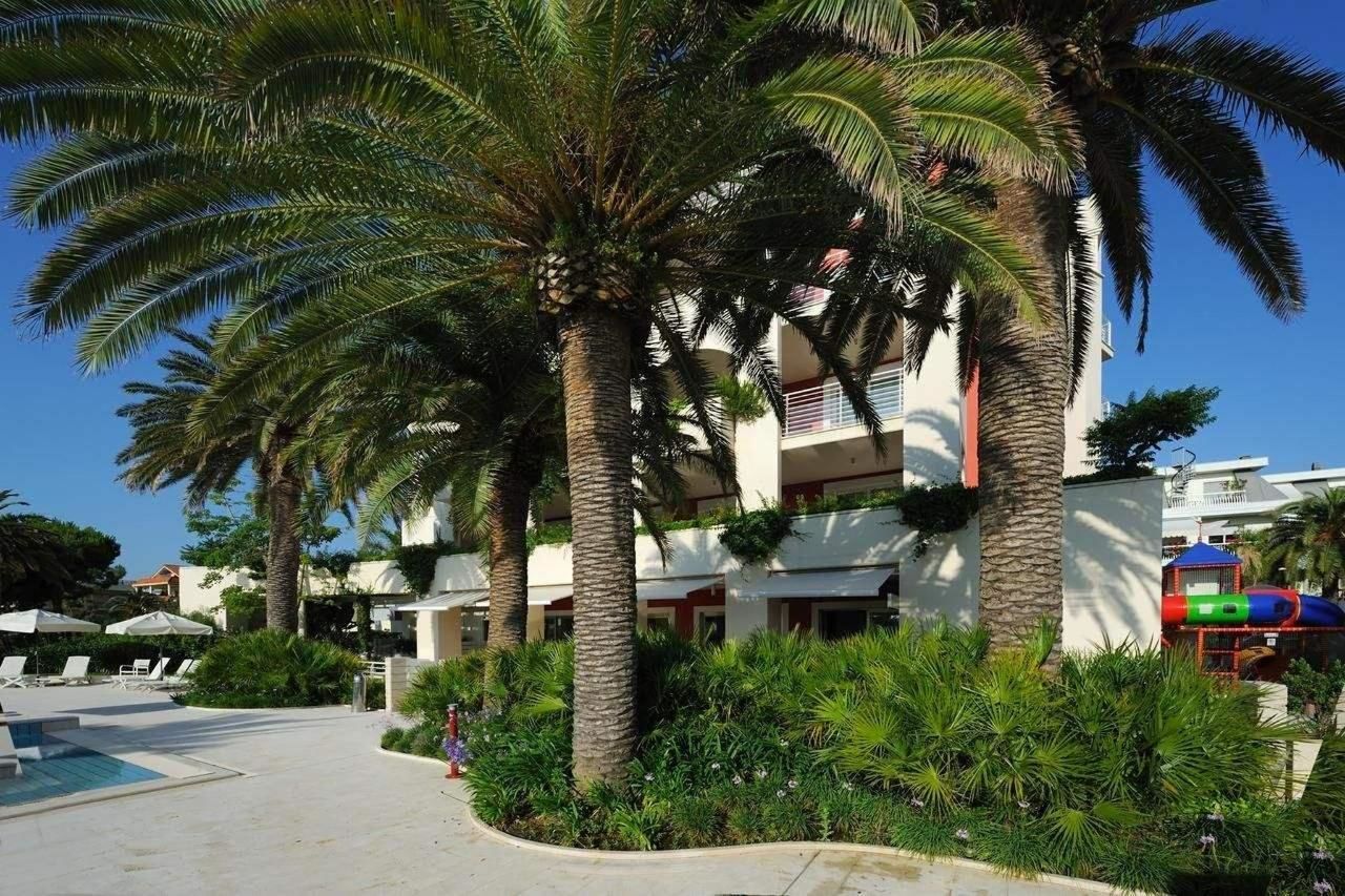 Un hotel con piscina, palmeras y área de juegos.