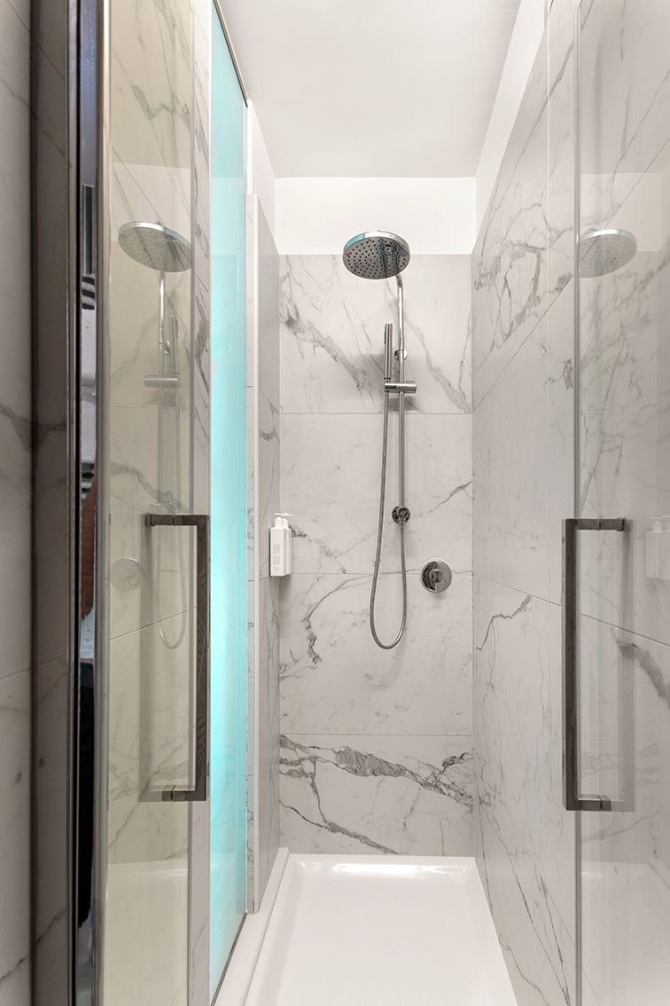 A modern shower with a handheld showerhead and a wall-mounted faucet.