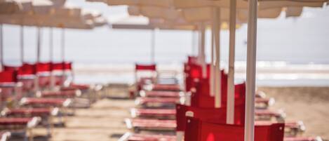 Strandstoelen en parasols staan in rijen op het zandstrand.