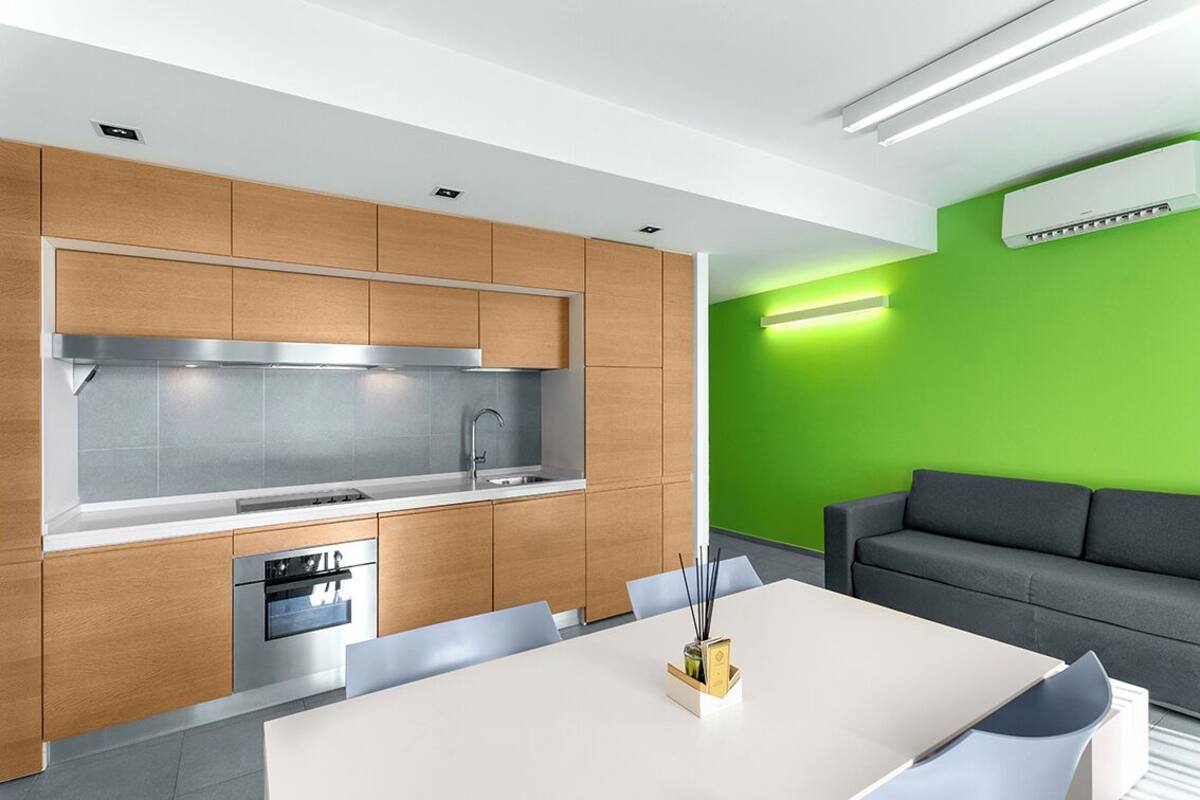 Una cocina moderna con gabinetes de madera, una campana extractora de acero inoxidable y un horno empotrado.
