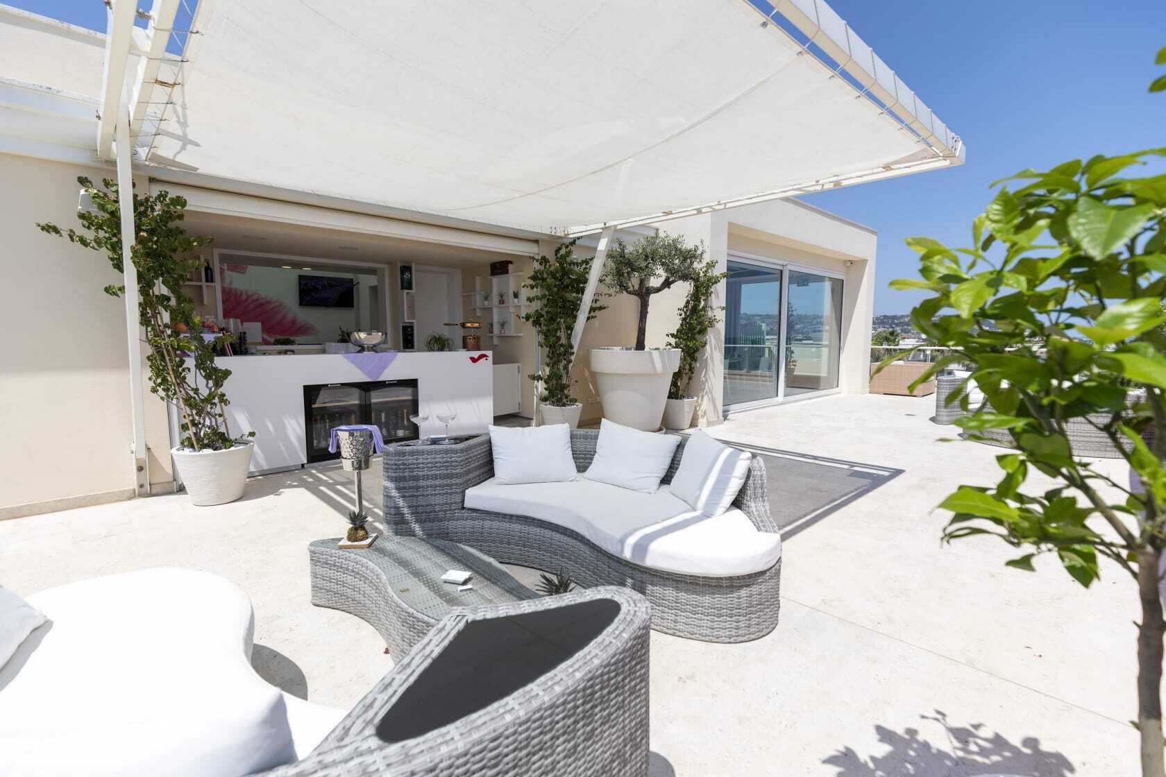 A rooftop terrace with outdoor seating, a bar area, and potted plants.