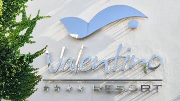 A sign for Valentino Resort with a stylized 'V' and the word 'Valentino' in a cursive font, along with the word 'RESORT' in capital letters.
