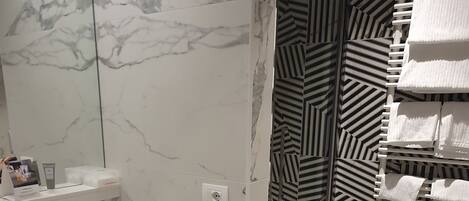 Un baño con lavamanos de mármol, un espejo, un inodoro con papel tapiz a rayas y una bañera.