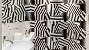 Un bagno moderno con parete a motivi geometrici, un lavandino rotondo e una zona doccia.