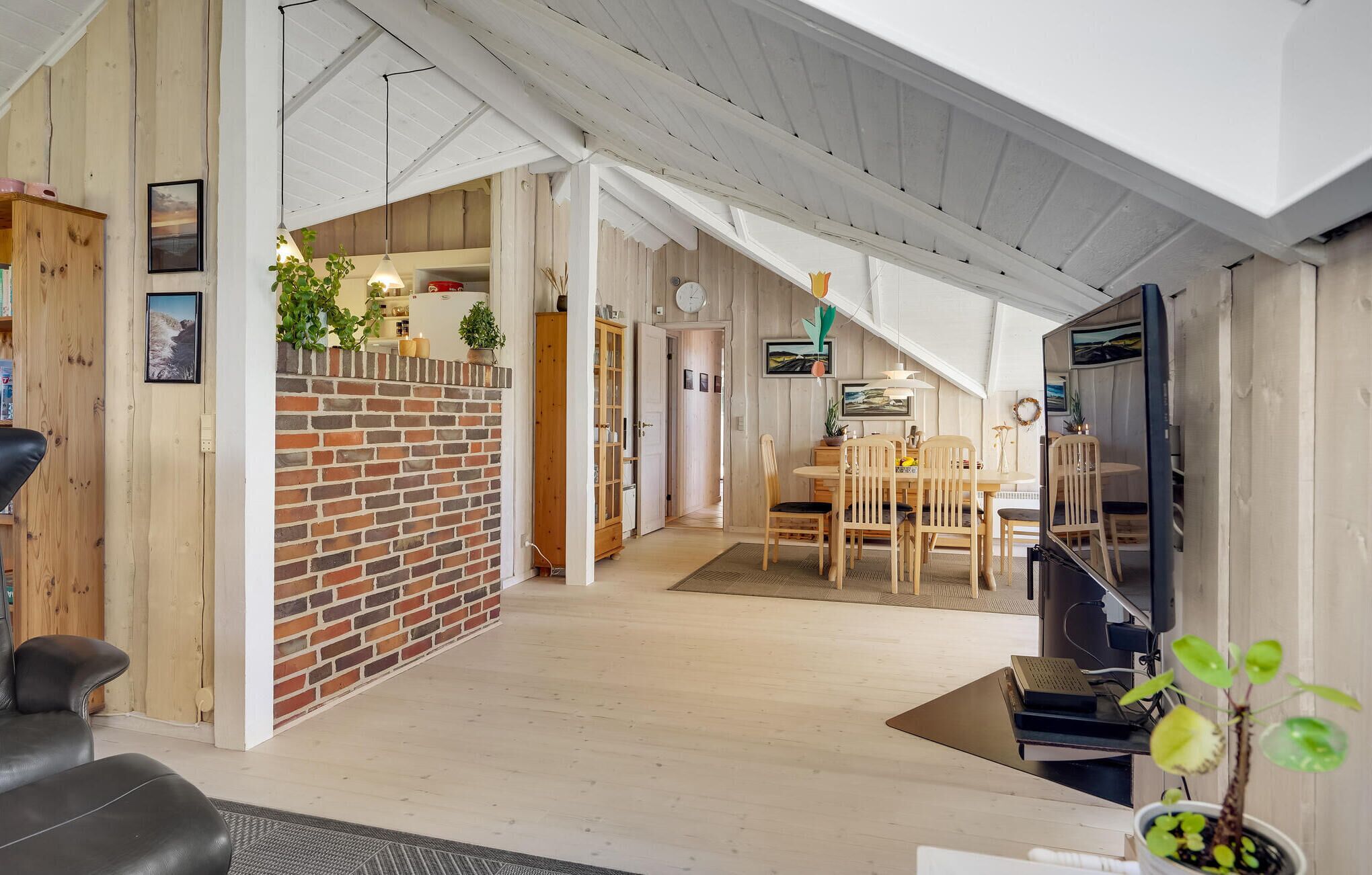 A spacious living area with a brick accent wall, wooden furniture, and a dining area with a table and chairs.
