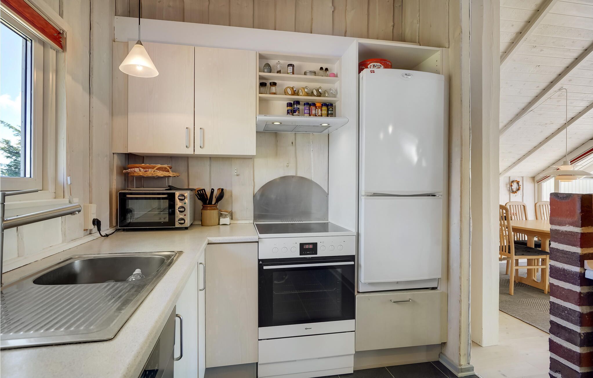 Een kleine keuken met een inbouwoven, een magnetron en een koelkast.