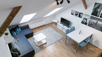 Een modern loftappartement met een woongedeelte, eethoek en een grote televisie.