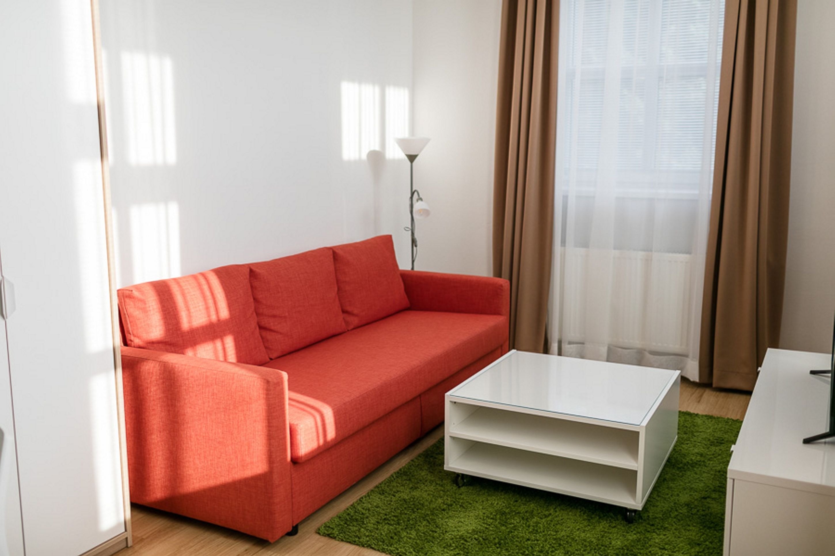 A modern living room with a red sofa, a white coffee table, and a green rug.