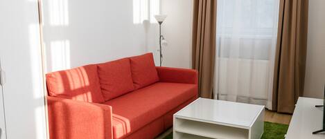A modern living room with a red sofa, a white coffee table, and a green rug.