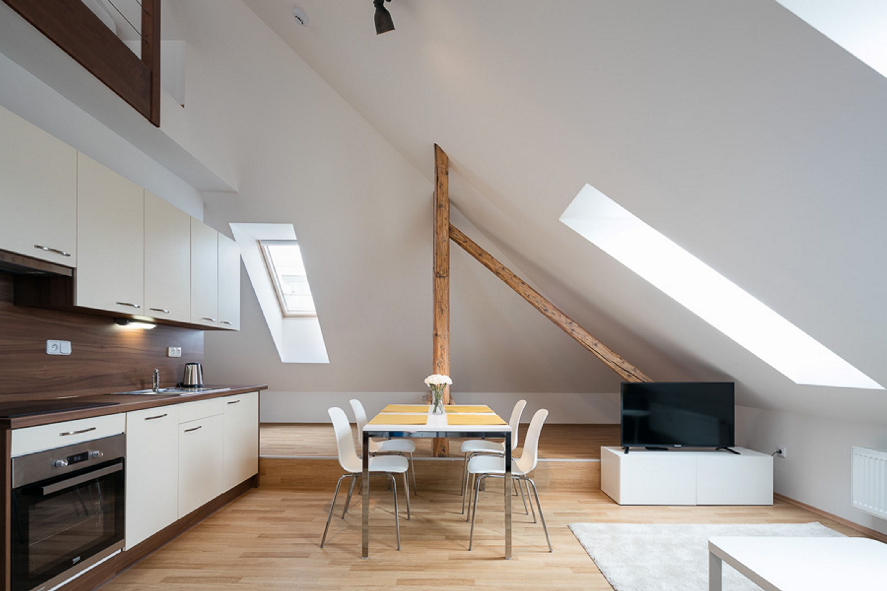 Una cocina moderna con armarios blancos, encimera de madera y horno integrado.