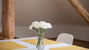 A table with a clear glass vase containing white flowers, set on a white tablecloth with yellow placemats.