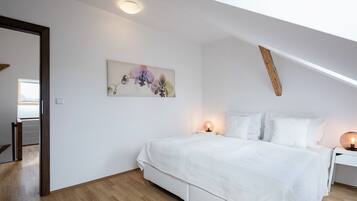 A bedroom with a large bed, a nightstand, a wall-mounted lamp, and a ceiling light.
