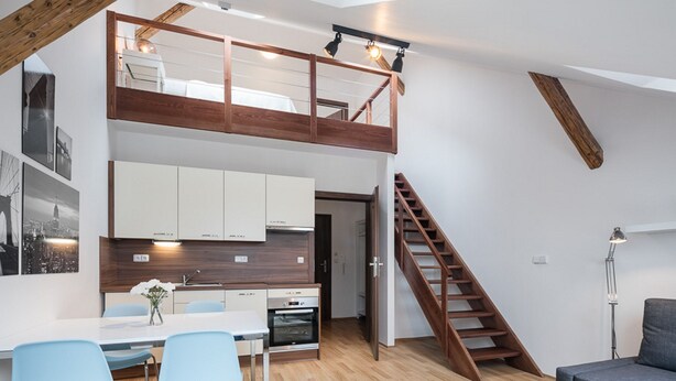 Un appartement moderne de style «loft», comprenant un coin repas, une cuisine et un escalier en bois.