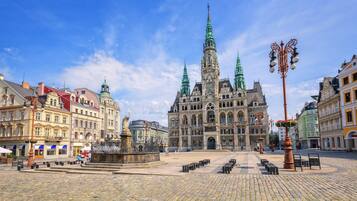 A historic square with a prominent church featuring twin spires, cobblestone pavement, and a central fountain.
