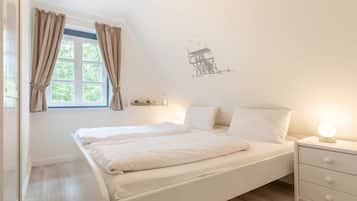 Ein Schlafzimmer mit einem Einzelbett, einem Nachttisch, einem Fenster mit Vorhängen und einer Wandsticker.
