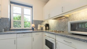 Een moderne keuken met witte kastjes, een Bosch vaatwasser, een magnetron en een gasfornuis.