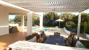 A covered outdoor area with a pool, lounge chairs, and a table with chairs. - Villa Chevalier at Kiotari Beach,  south of Lindos (Dodekanissos)