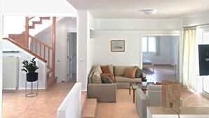 A spacious living area with a sofa set, a coffee table, and a television. A staircase is visible in the background leading to another room. - Villa Chevalier at Kiotari Beach,  south of Lindos (Dodekanissos)