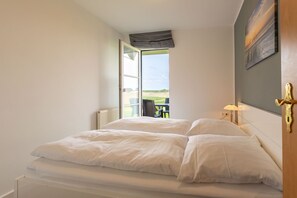 A bedroom with a bed, a window, a chair, and a lamp.