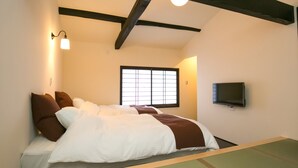 A hotel room with a bed, a television, and a window with a grid pattern. - Nijo Yu-Rakukan (Kyoto)