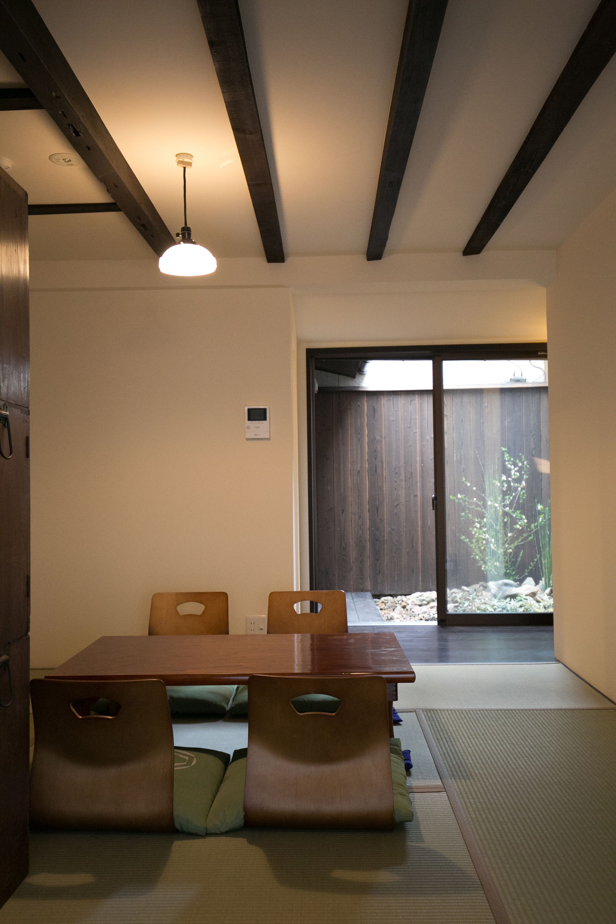 A traditional Japanese-style room with tatami flooring, a low wooden table, and a sliding door leading to a garden.