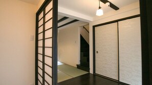 A hallway with a traditional sliding door, a staircase, and a ceiling light fixture. - Nijo Yu-Rakukan (Kyoto)