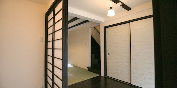 A hallway with a traditional sliding door, a staircase, and a ceiling light fixture.