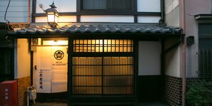 A traditional Japanese building with a tiled roof, a lantern, and a sign with Japanese characters.