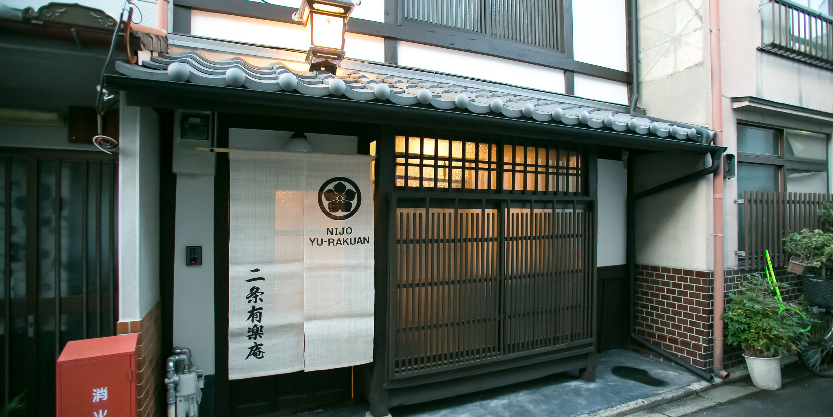 Un edificio japonés tradicional con techo de tejas, puerta de madera y un cartel que dice "NIJO YU-RAKUAN".