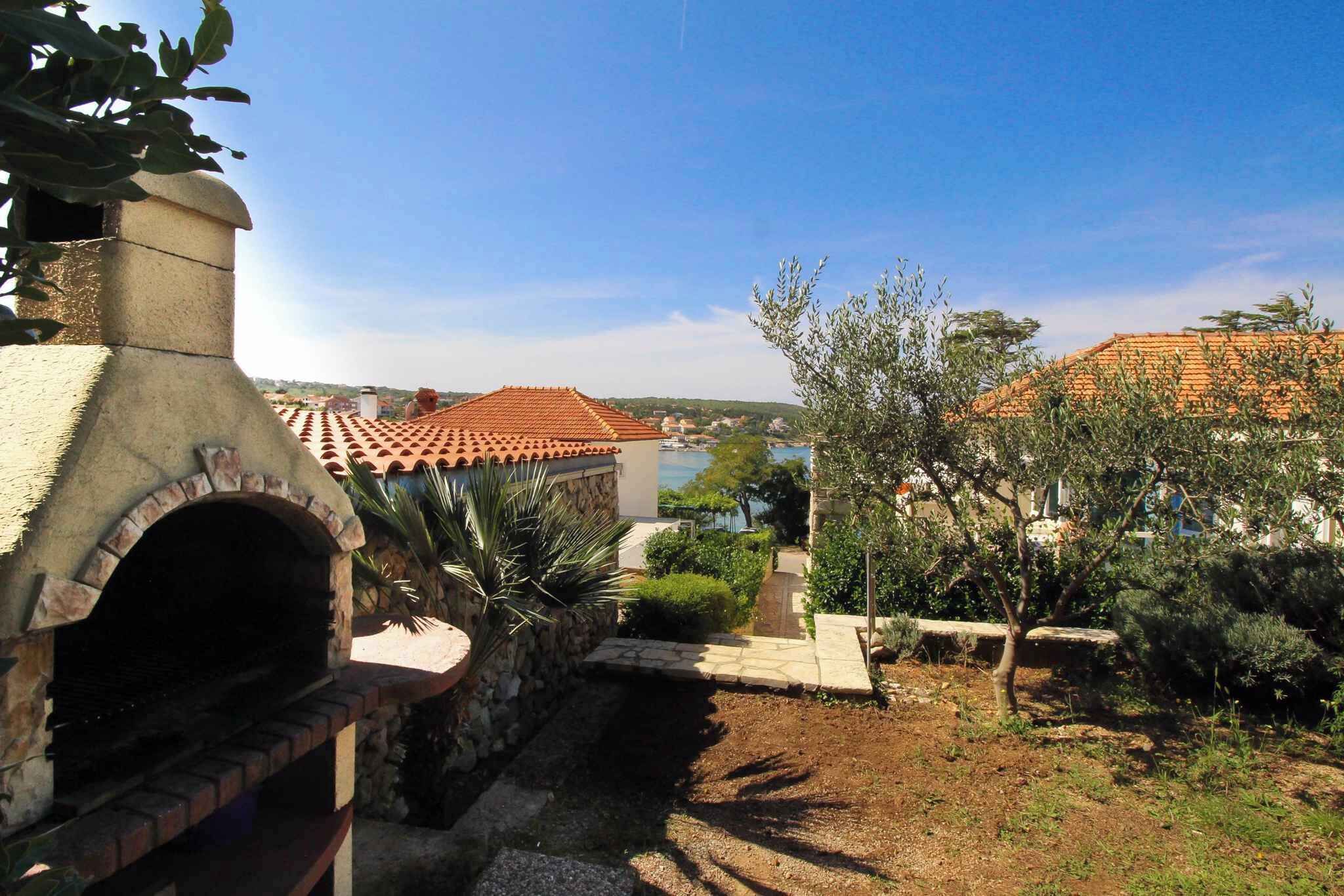 A stone oven, a garden with a small pond, and a view of a town with red-roofed buildings.