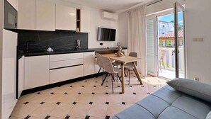 Et moderne køkken med hvide skabe, en sort bordplade og et spiseområde med et bord og stole.