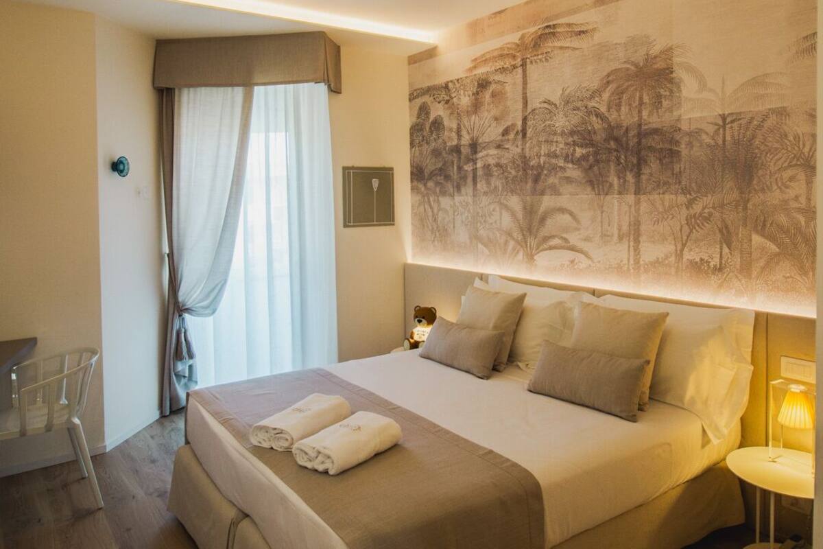 A hotel room with a large bed, a desk, and a chair.