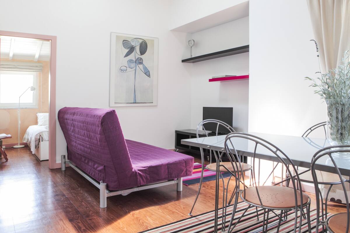 Habitación moderna con cama, escritorio y silla. Hay un cuadro en la pared y una planta en la mesa.