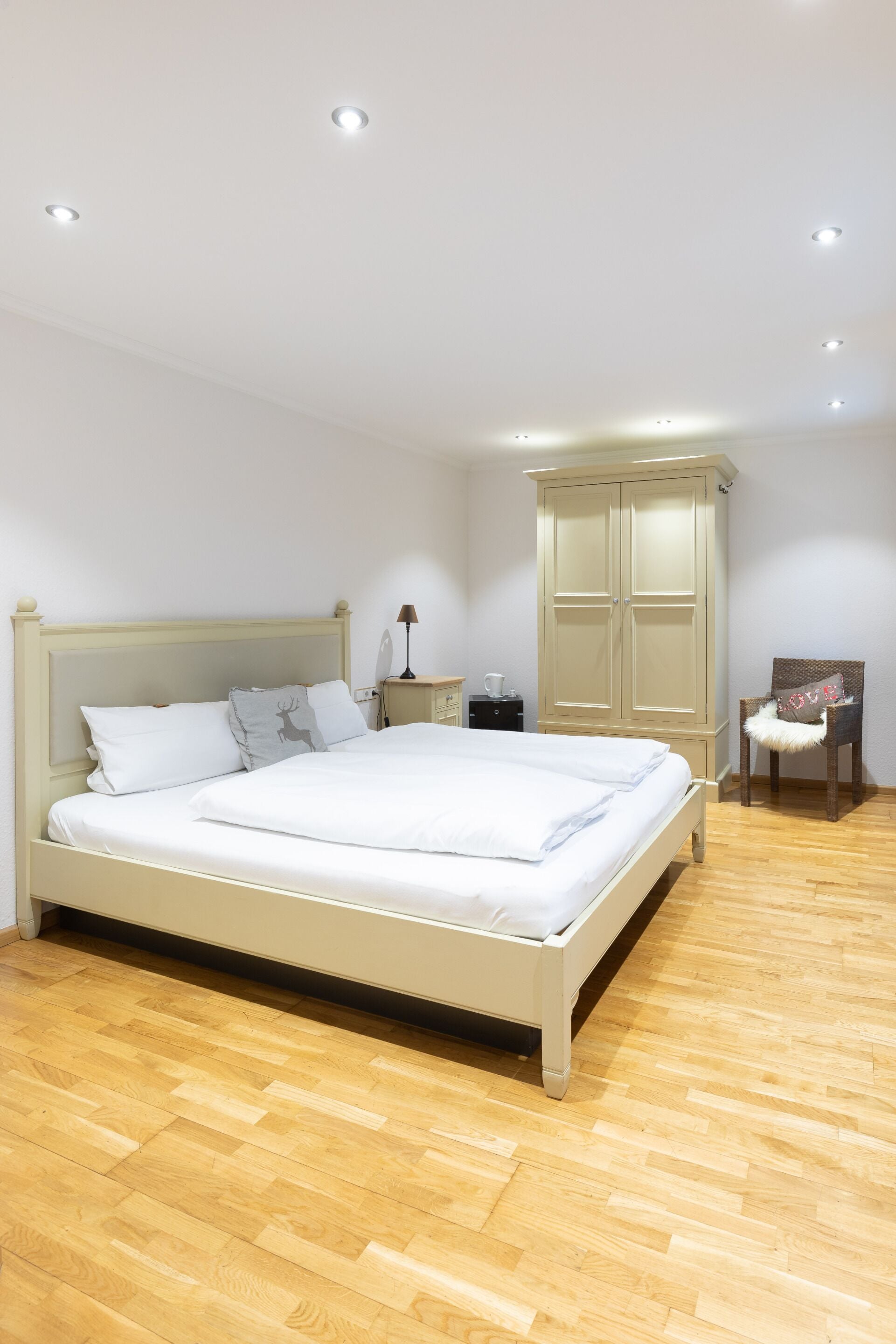 A bedroom with a bed, a wardrobe, a chair, and a nightstand.