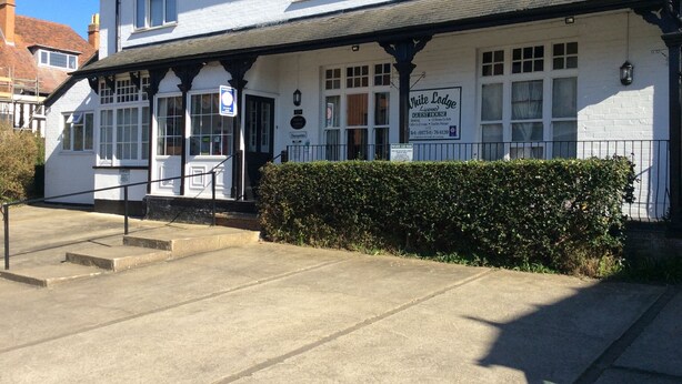 A white building with a sign reading "White Lodge" and a blue sign indicating a car park. - White Lodge Guest House (Skegness)
