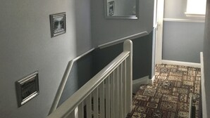 A staircase with a patterned carpet, a white railing, and a wall-mounted light fixture. - White Lodge Guest House (Skegness)