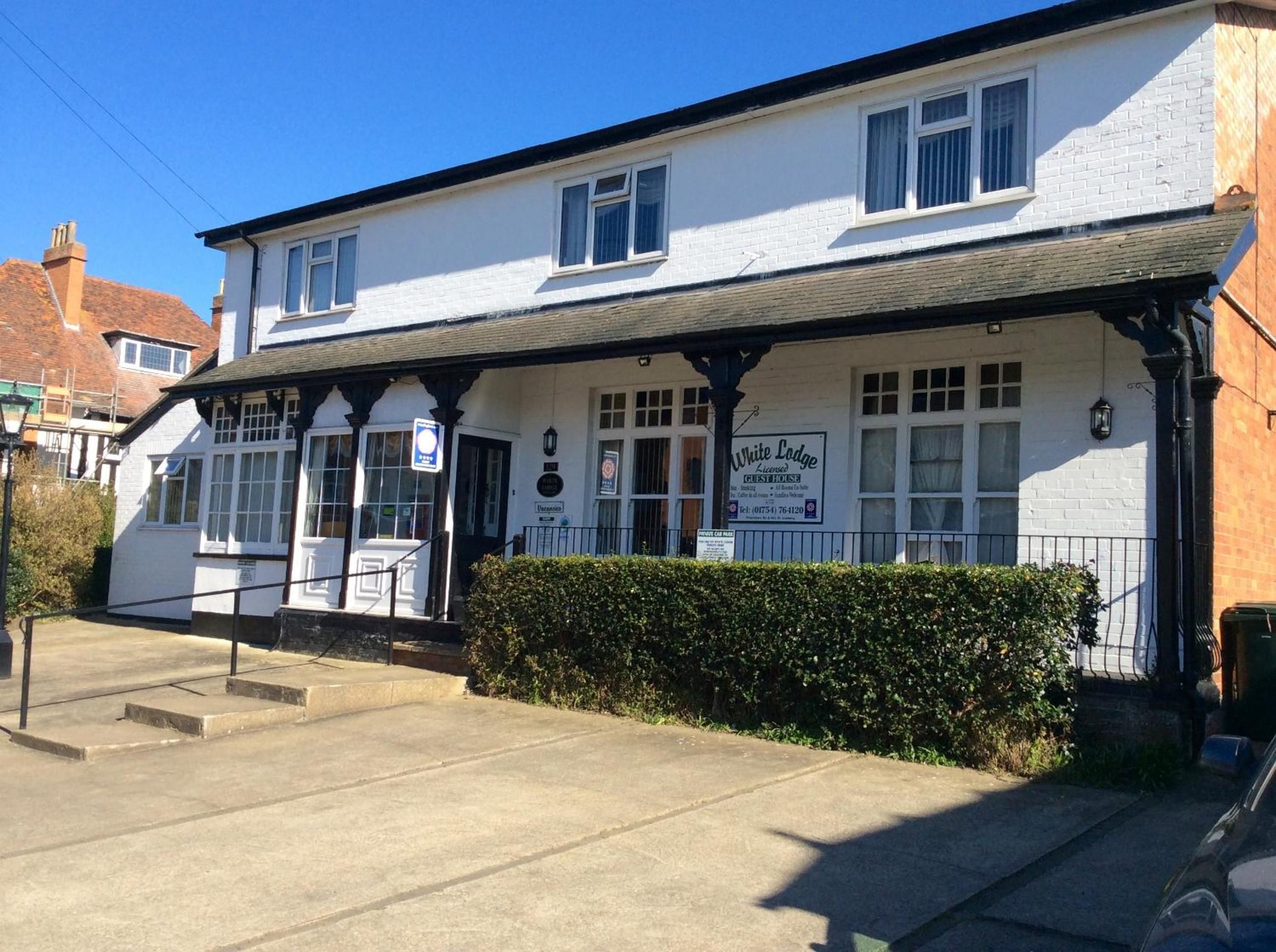 A two-story building with a sign indicating it is a licensed guesthouse.
