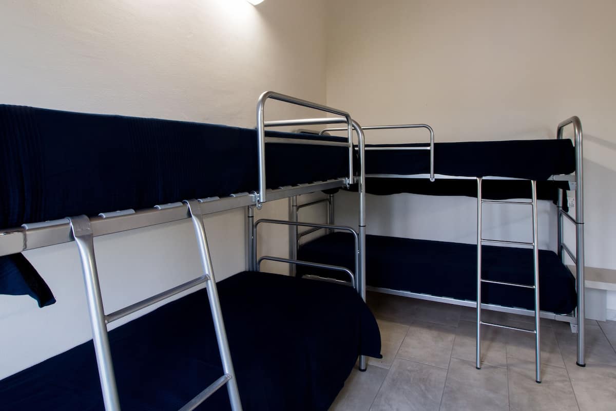 Asuntolan huone, jossa on kerrossängyt, pieni työpöytä ja tuoli.
