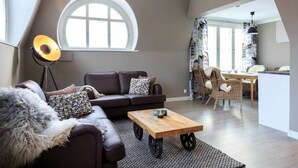 A modern living room with a brown leather sofa, a wooden coffee table, and a large window. - Harmooni Suites (Jyväskylä)