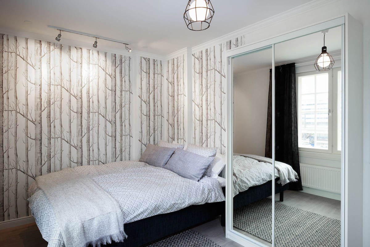 A bedroom with a bed, a mirror, and a window.