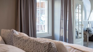 A bedroom with a bed, a window, and a view of the outside. - Harmooni Suites (Jyväskylä)