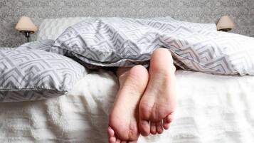 Una cama con almohadas estampadas y un edredón blanco liso.
