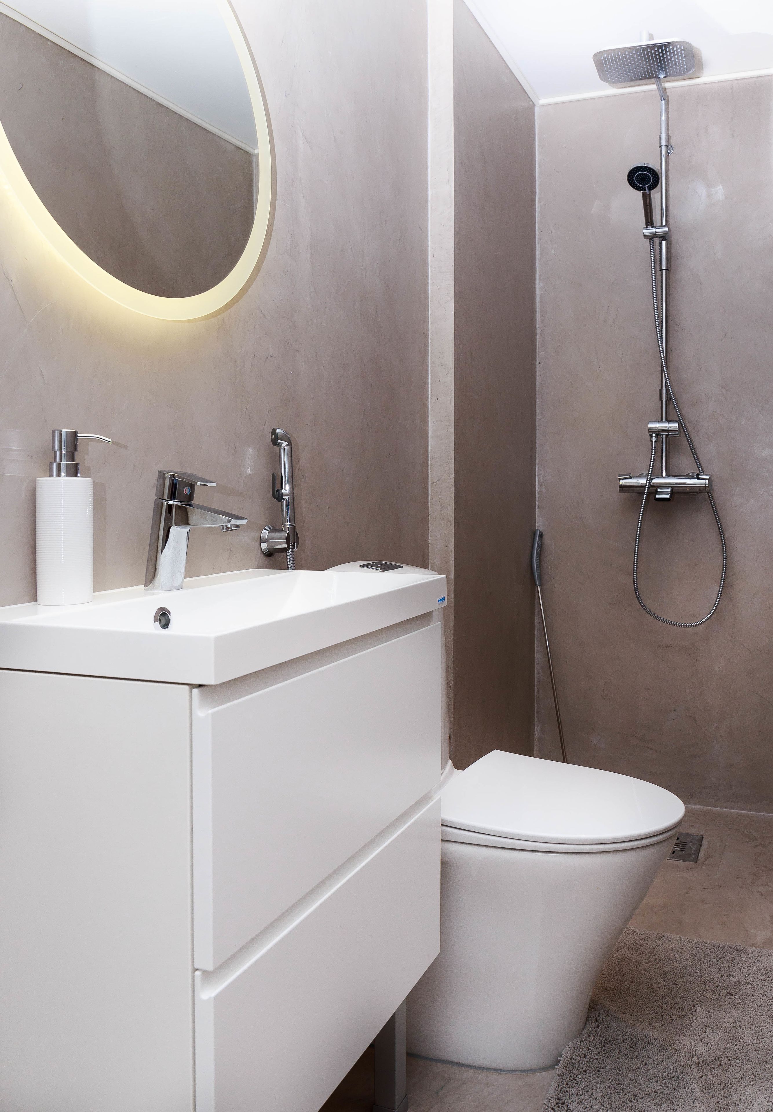 A modern bathroom with a white sink, a toilet, and a shower.