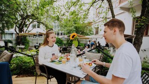 An outdoor dining area with a table, chairs, and a sunflower decoration. - Harmooni Suites (Jyväskylä)