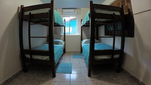 A dormitory room with two bunk beds, a window with a view, and a tiled floor.